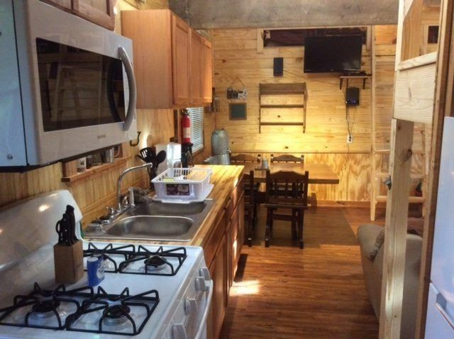 Narrow kitchen with white stove, wooden cabinets, and dining table in a warm-lit apartment