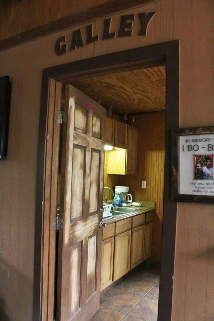 Entrance to a gallery with a wooden door and display window, lit by a warm interior lamp.
