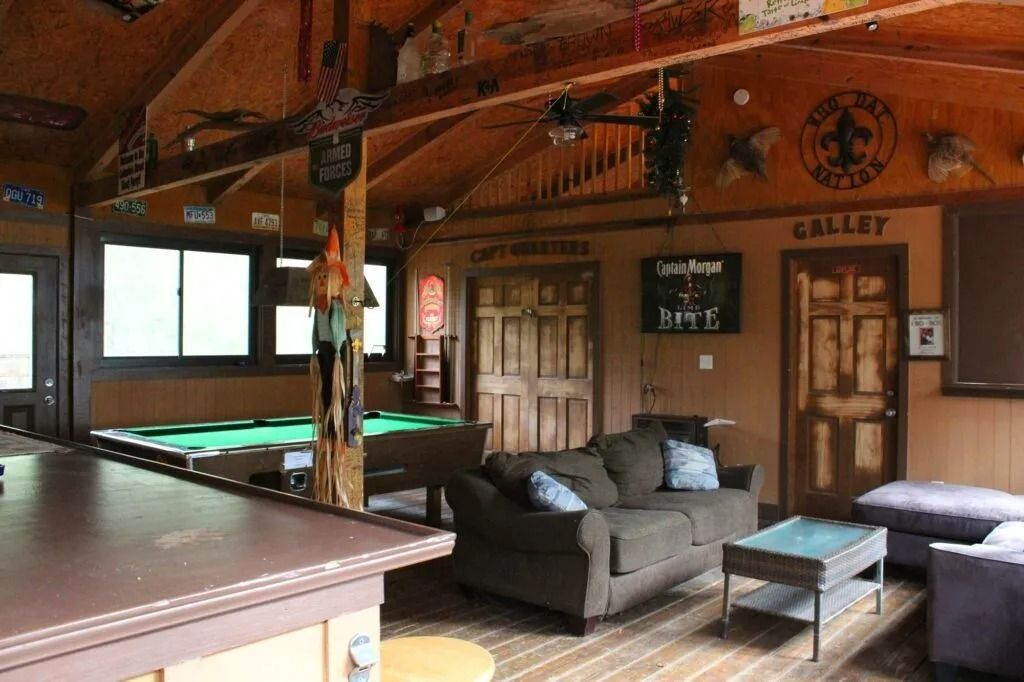 Rustic lodge game room with pool table, couch, and wood-paneled walls