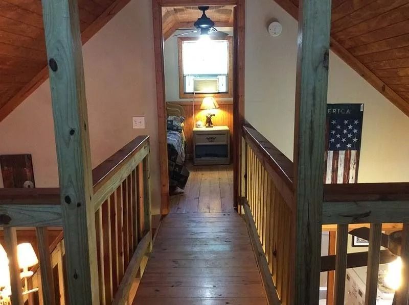 Wooden loft hallway with stairs, a desk lamp, and an American flag on the wall