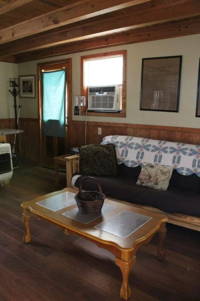 Cozy living room with wood beams, sofa, coffee table, and window air conditioner