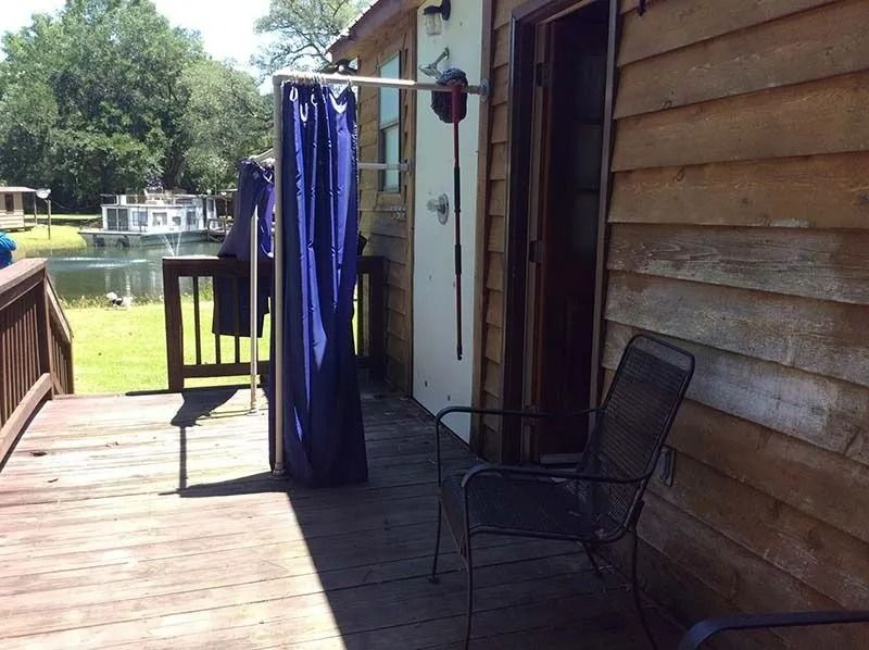 Wooden porch with a black chair and blue hanging curtain beside a lakeside view