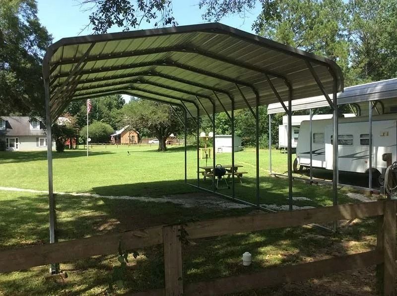 Covered picnic shelter with metal roof in a grassy park beside an RV.