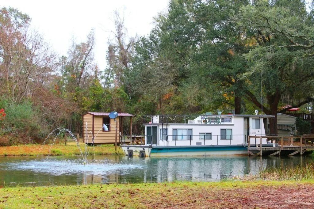 Houseboat on a pond surrounded by autumn trees and grass