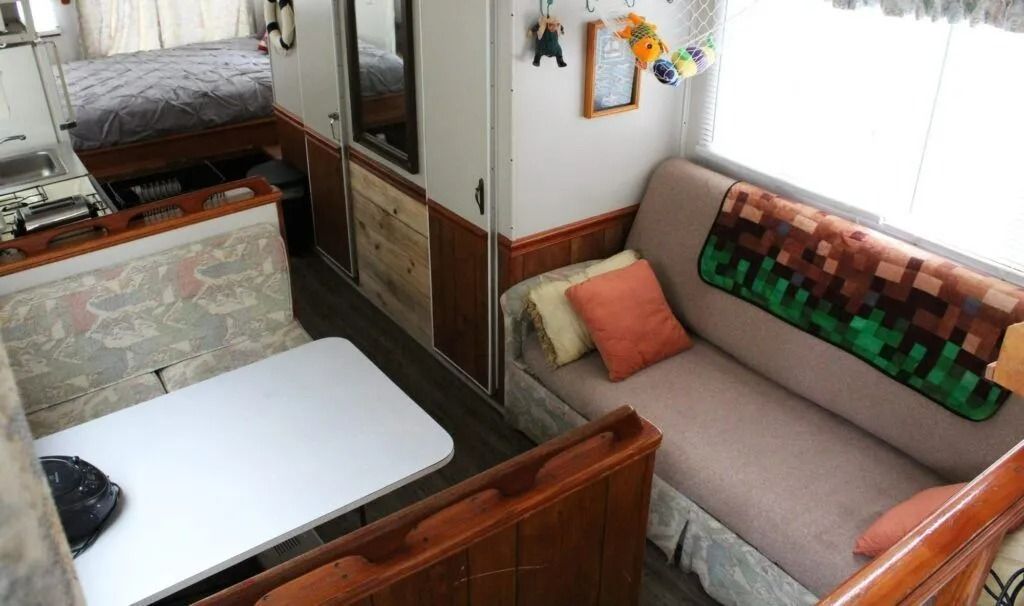 Cozy RV interior with two cushioned benches, a small table, and window light.