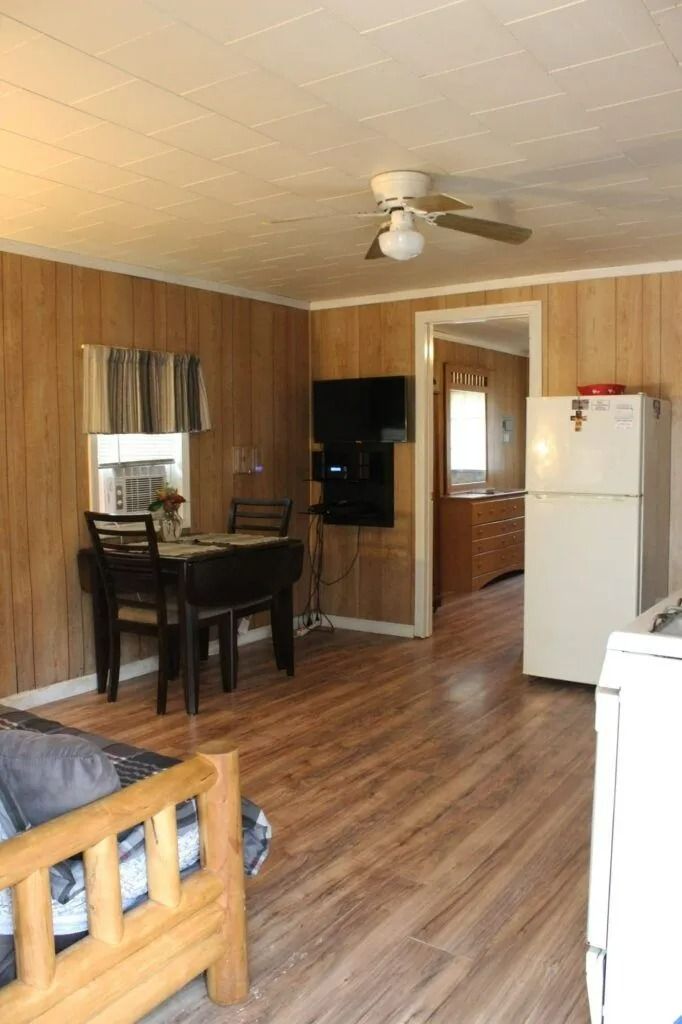 Small wood-paneled kitchen and dining area with table, ceiling fan, and white refrigerator.
