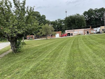 A lawn mower is cutting a lush green lawn in a backyard.