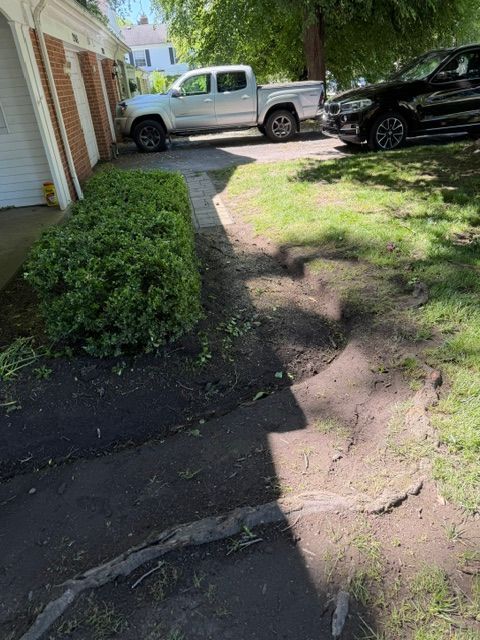 Front yard path beside a house with a silver pickup truck and black SUV parked nearby
