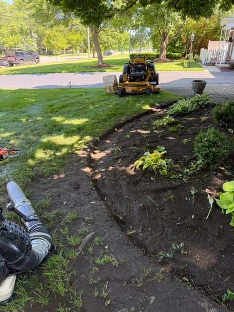 Garden worksite with a skid steer beside a freshly dug planting bed and scattered soil.