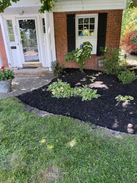 Front yard garden bed with mulch and hostas beside a brick house entrance.