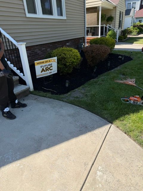 Person on a porch beside an APC sign, with a lawn and sidewalk in front of a house.