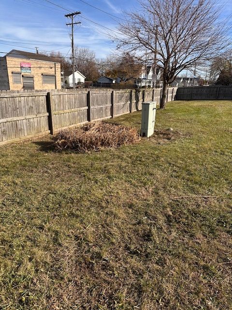 Grassy yard beside a wooden fence, with a utility box and leafless tree in winter light