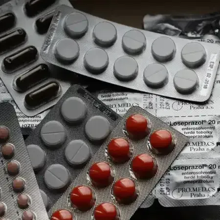Pills in blister packs: brown capsules, white and red round tablets. Close-up on several medication packages.