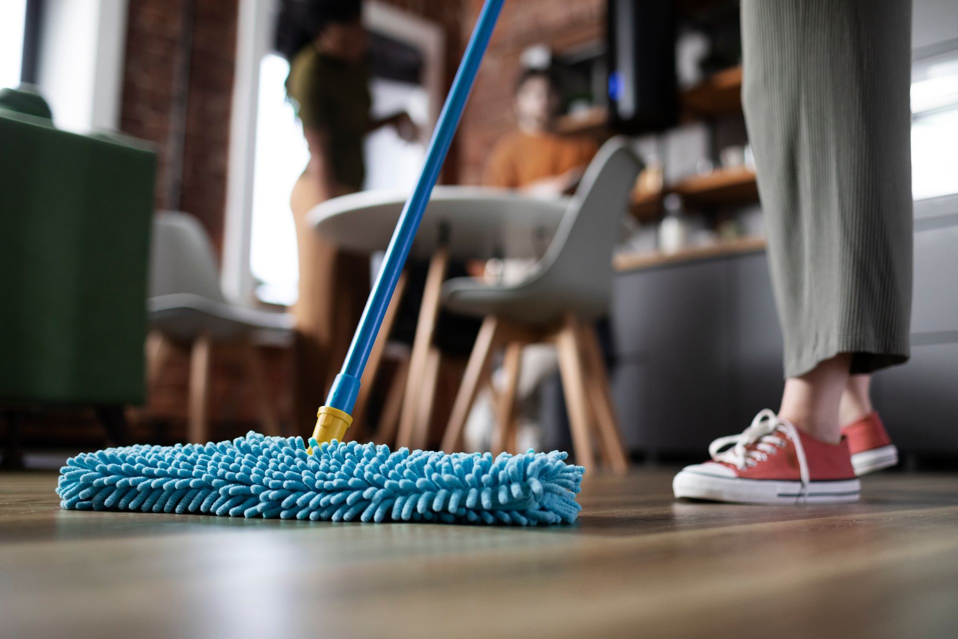 Lady cleaning her apartment luxury vinyl with roommates in background.