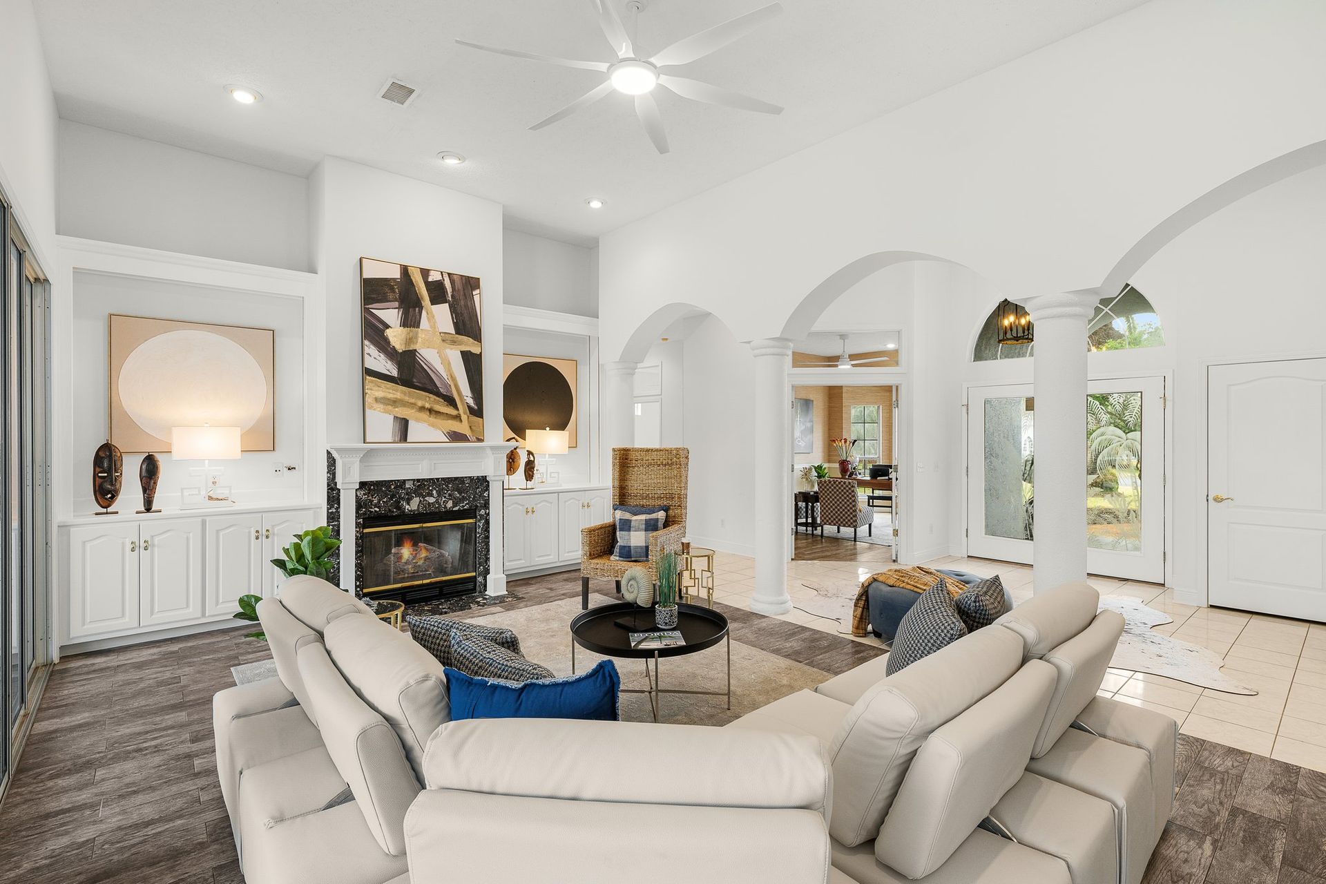 Bright modern living room with white sectional sofa, fireplace, arched windows, and light wood floors