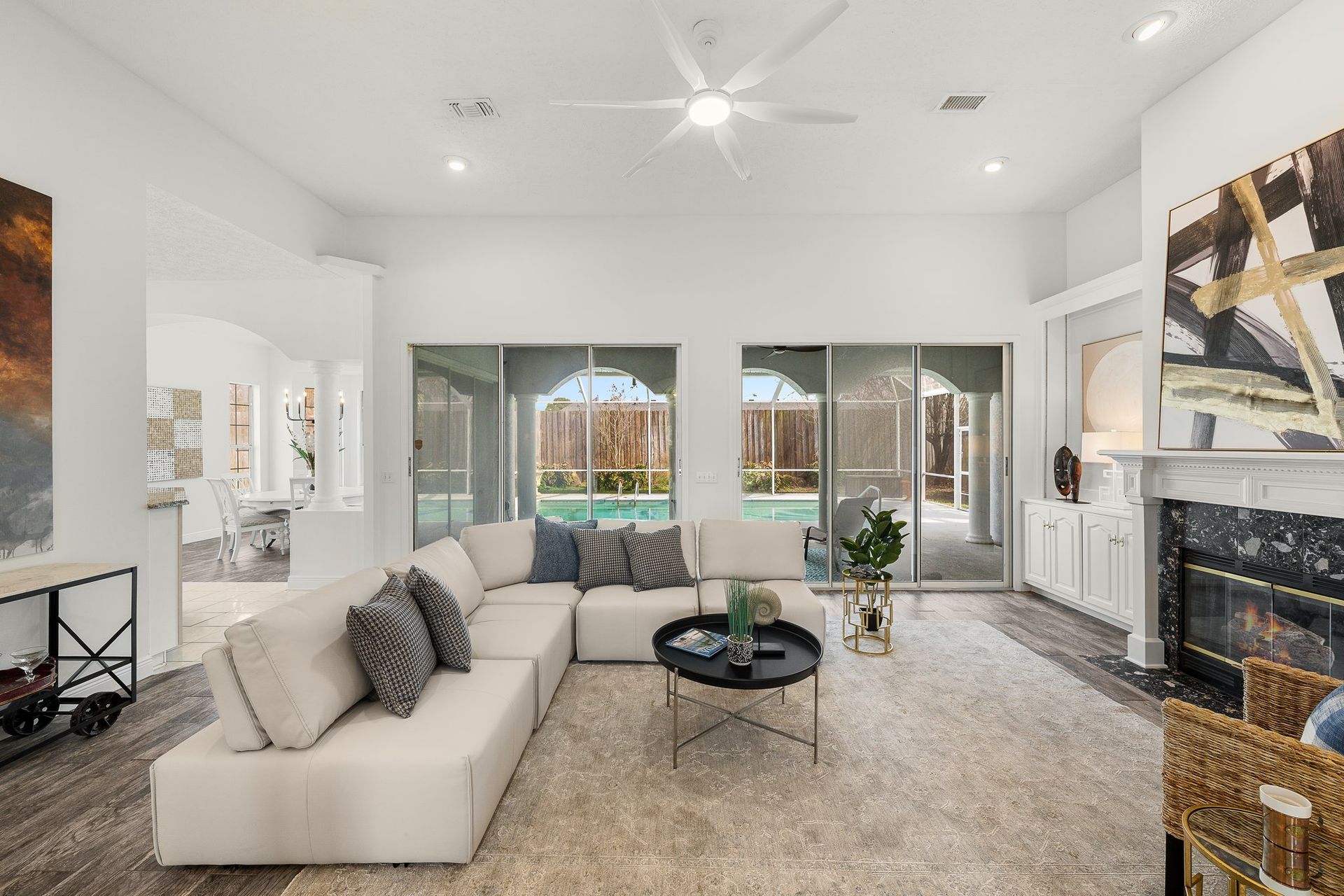 Bright modern living room with a white sectional, fireplace, and large windows overlooking a patio.