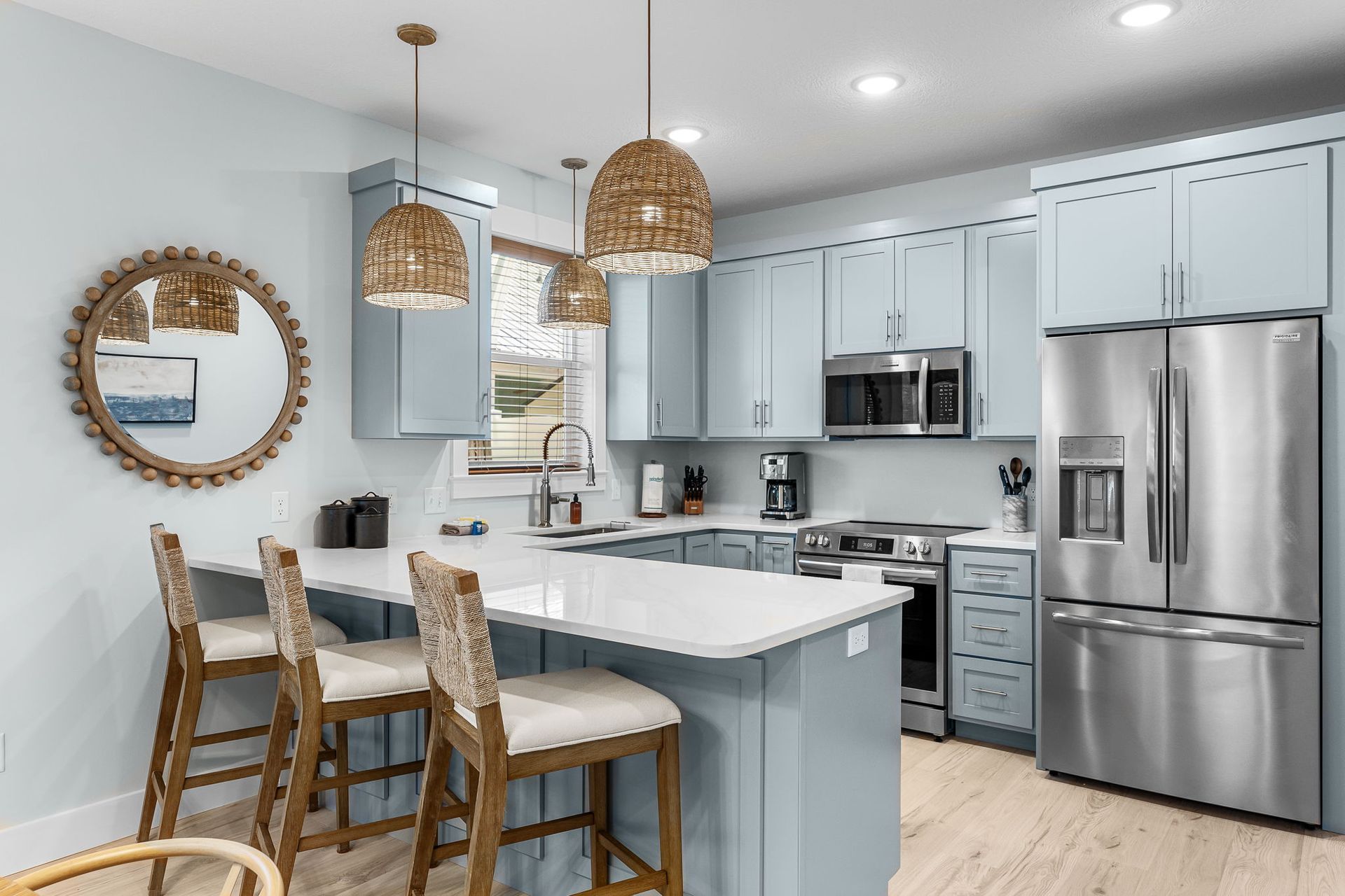 Modern kitchen with white cabinets, stainless appliances, island, and woven pendant lights