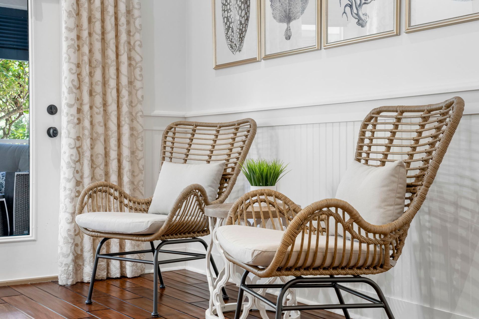 Two wicker chairs with white cushions in a bright living room by a glass door