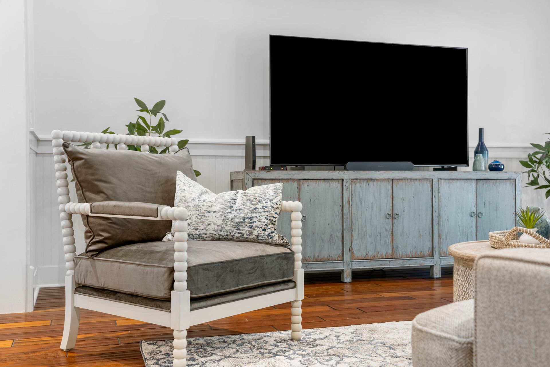 Cozy living room with wicker chair, large TV on a blue cabinet, and hardwood floors