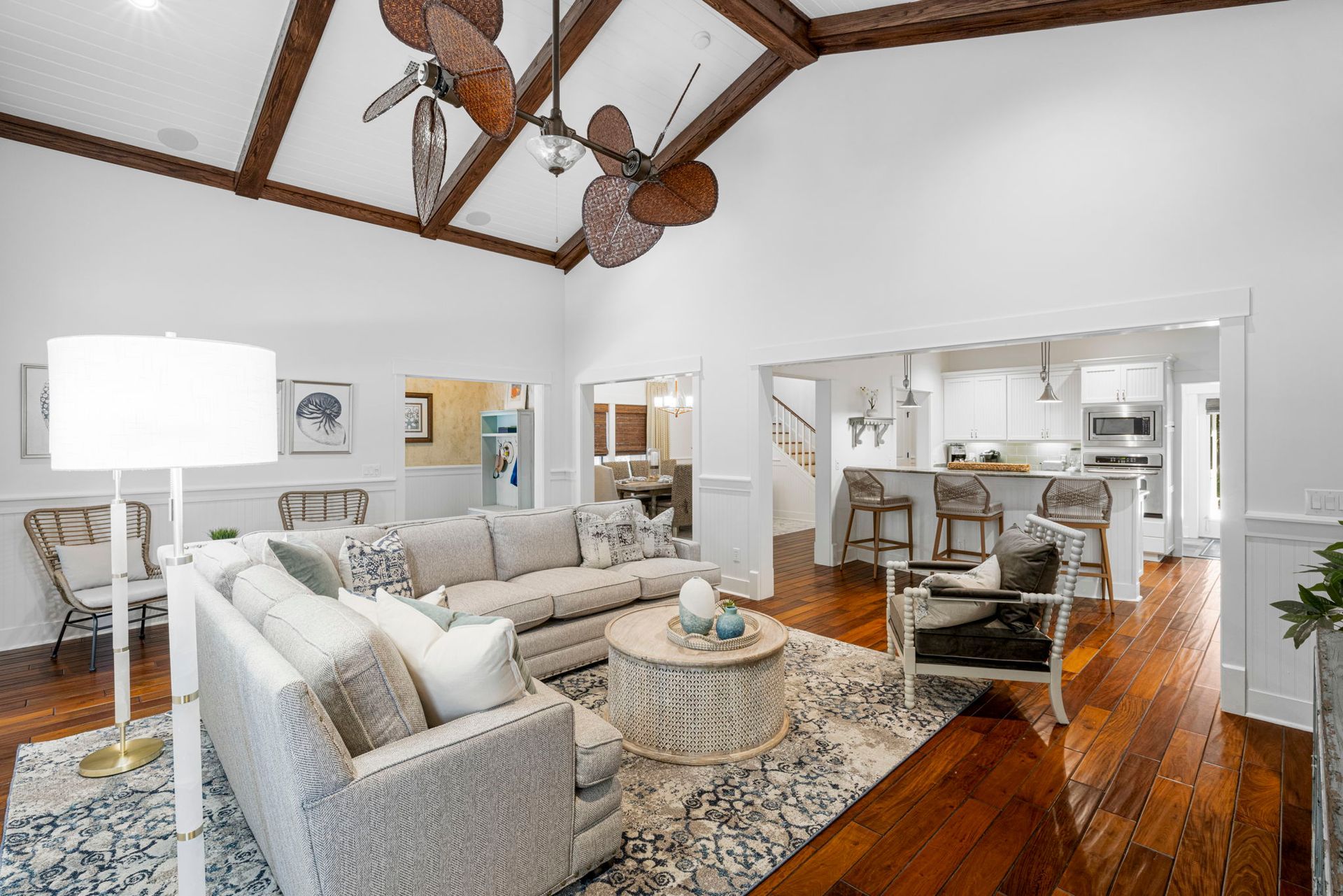Spacious living room with sectional sofa, patterned rug, wood floors, and open kitchen-dining area