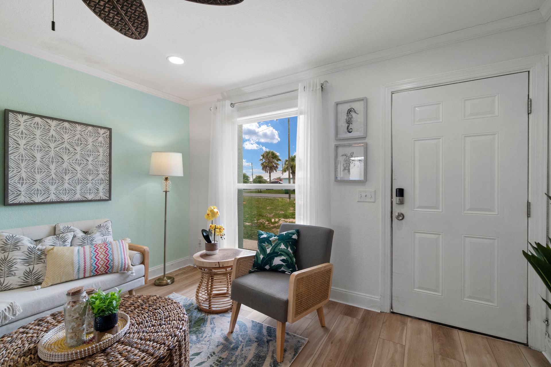 Bright living room with mint wall, gray chair, floral sofa, window, and white door