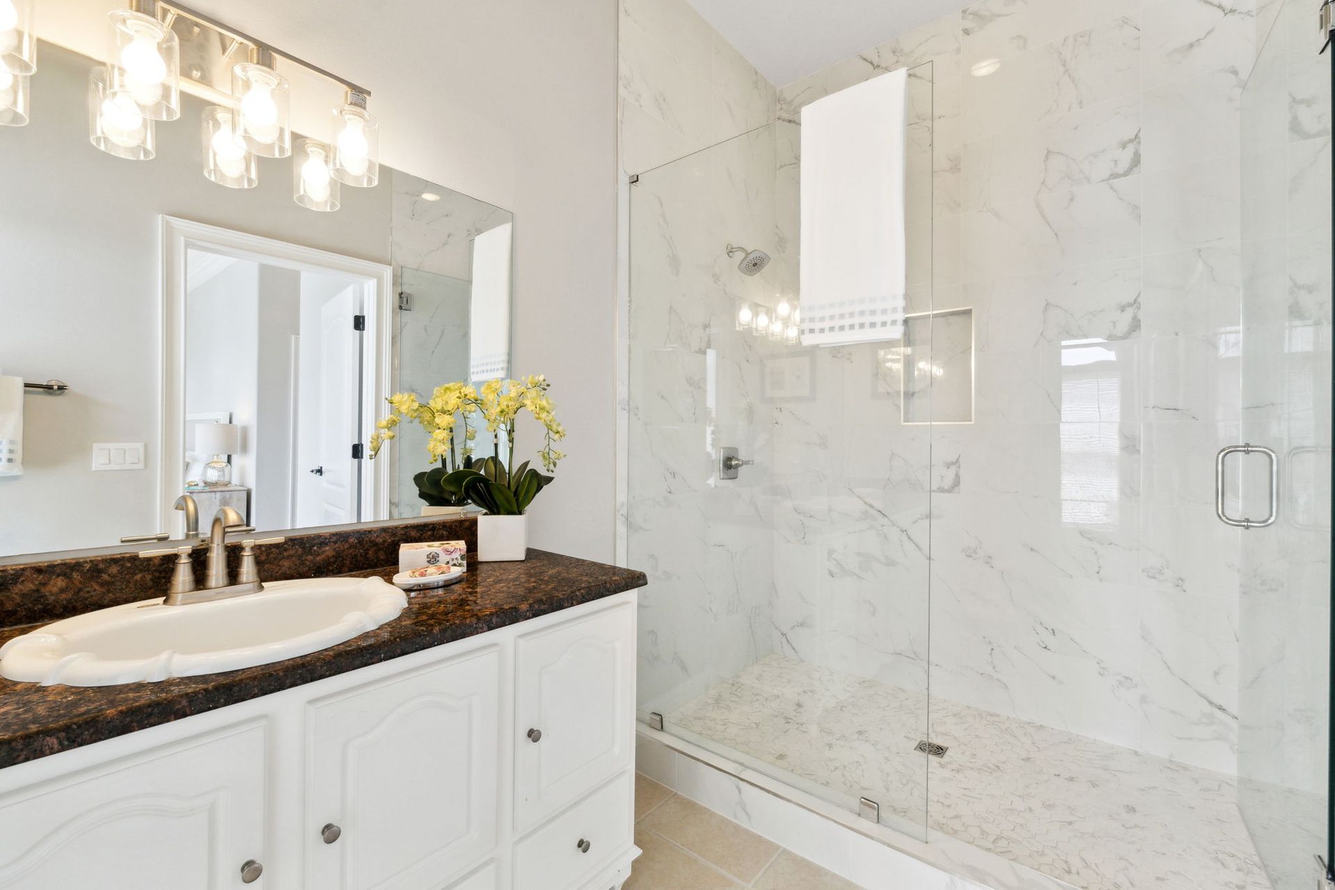 Bright bathroom with double vanity, large mirror, and glass shower