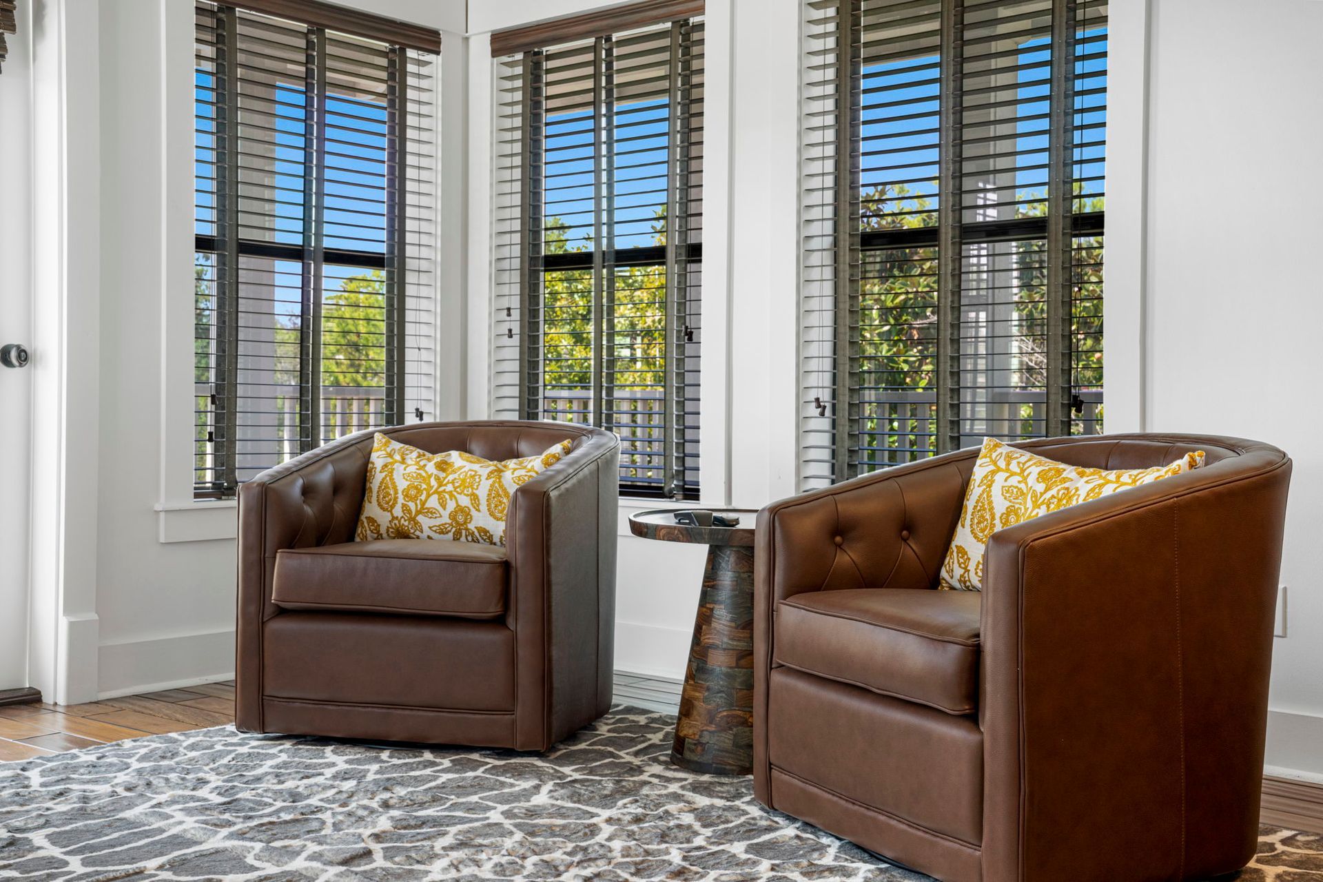Two brown armchairs by tall windows in a bright living room