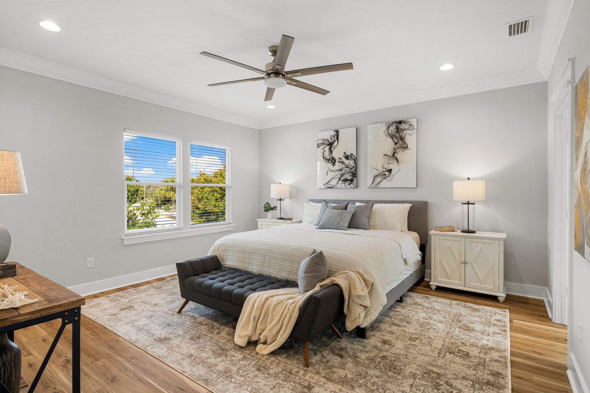 Bright bedroom with a king bed, large window, gray walls, beige rug, and modern decor