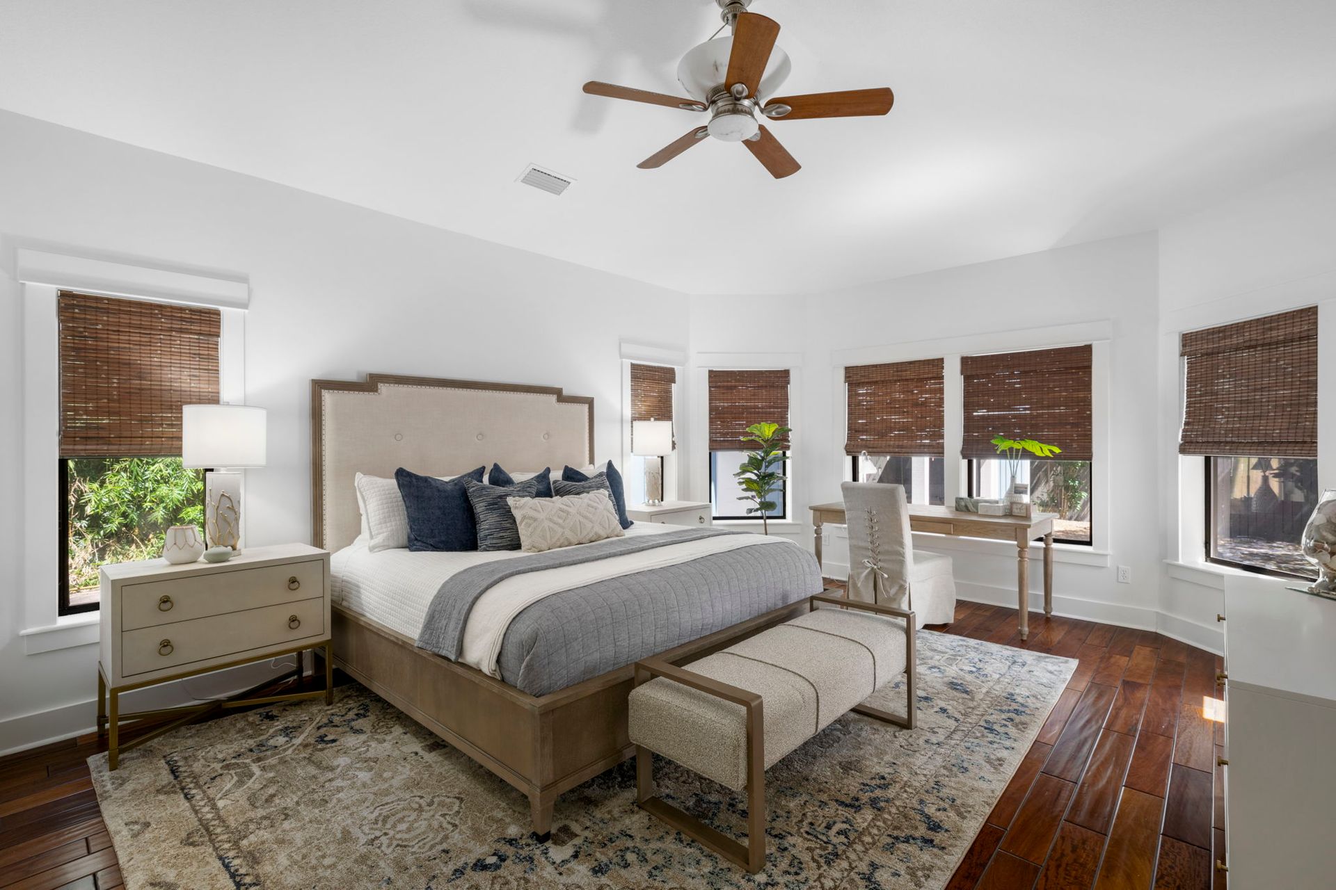 Bright bedroom with a bed, benches, wood floors, windows, and a ceiling fan