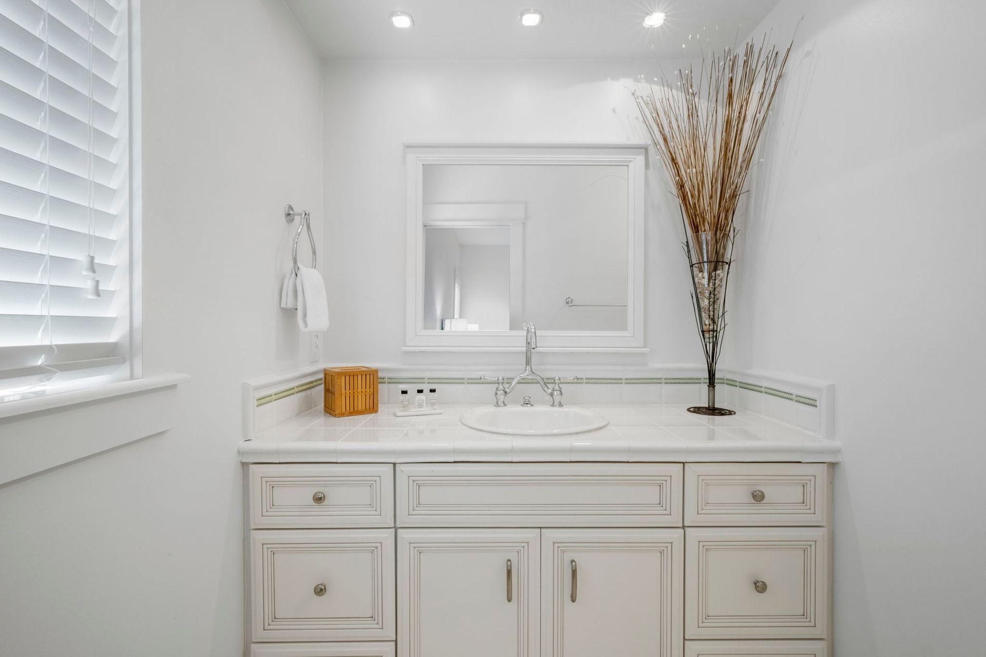 White bathroom vanity with mirror, sink, and decor in a bright minimalist setting