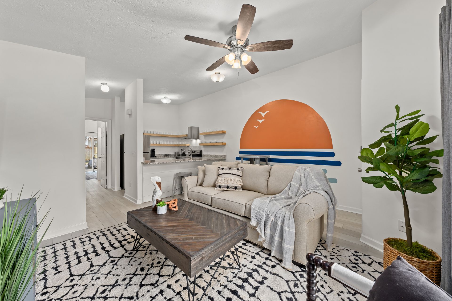 Modern living room with gray sofa, wood coffee table, patterned rug, and orange-and-blue wall mural