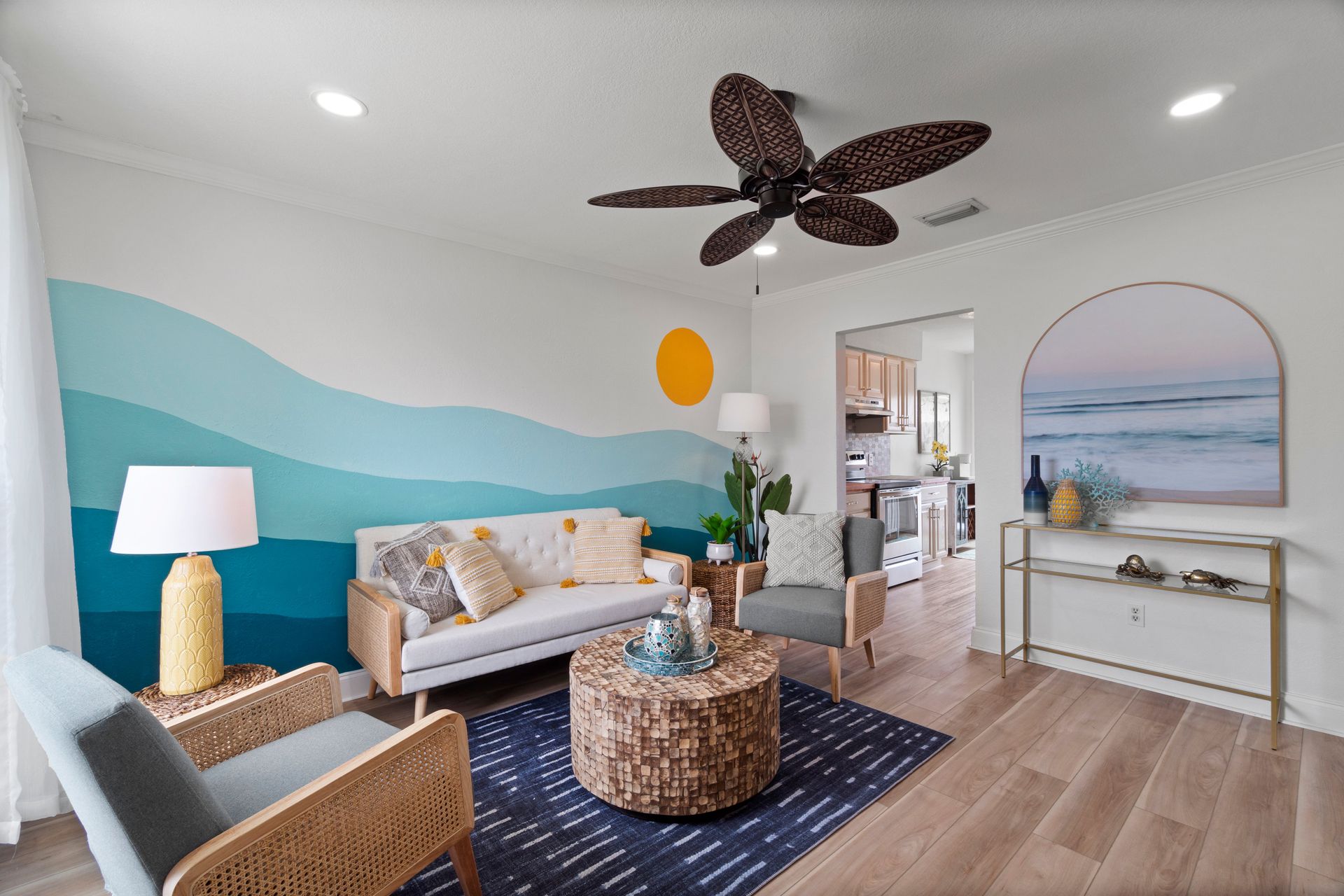 Bright boho living room with teal wave wall, white sofa, wicker furniture, and ceiling fan