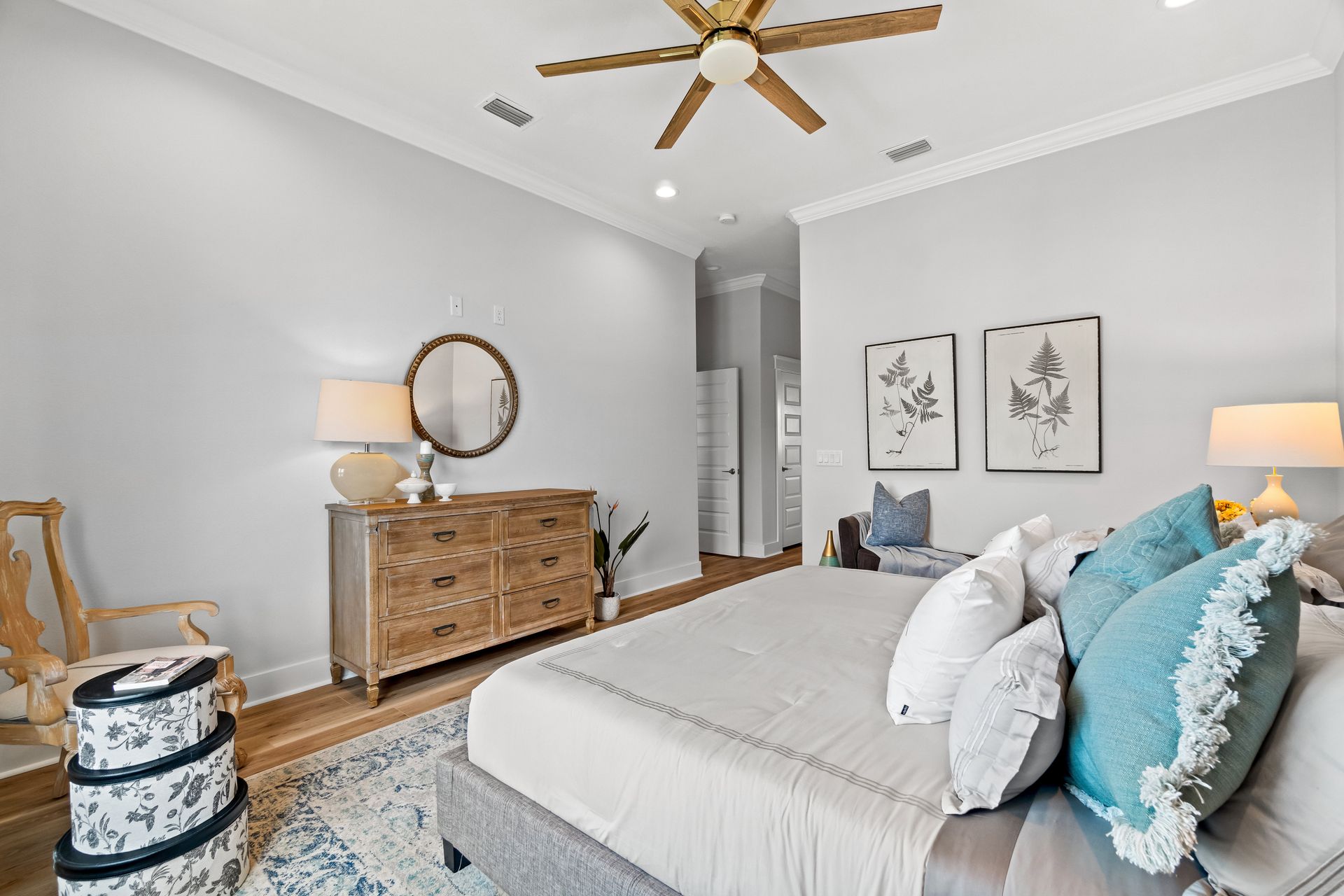 Bright bedroom with gray walls, white bed, wooden dresser, and blue accents