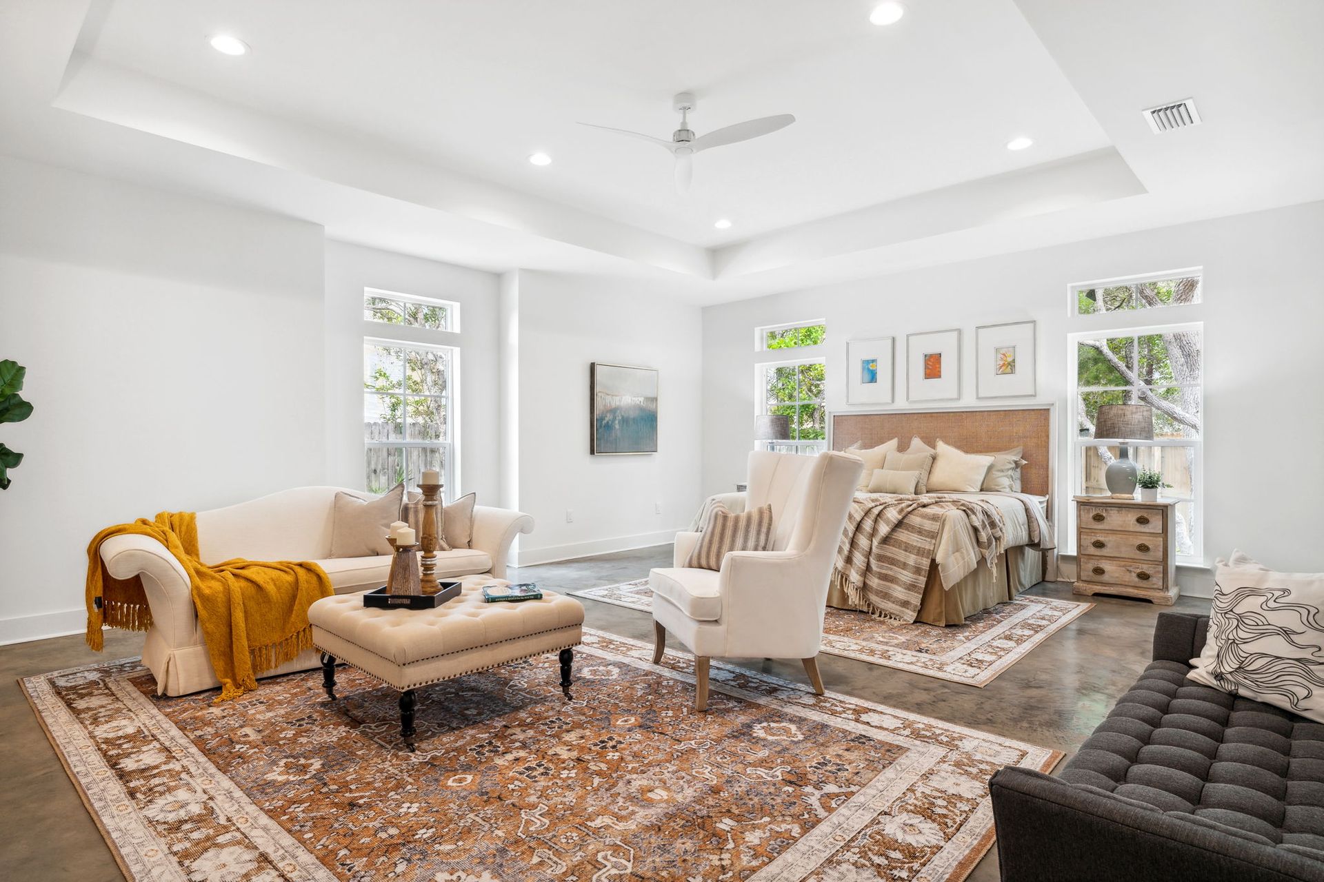 Bright, airy bedroom with white walls, patterned rugs, beige bed, and a mustard throw blanket
