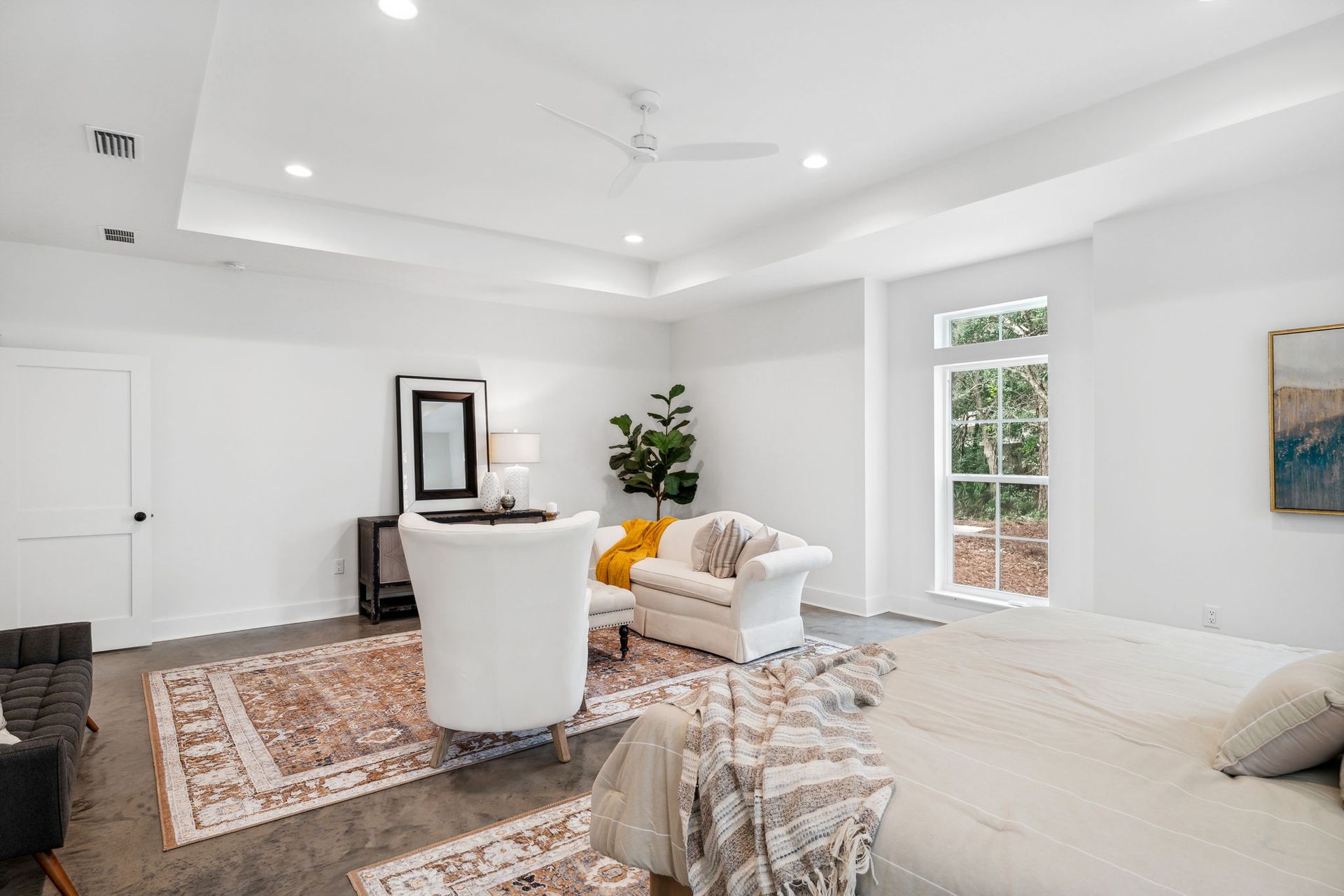 Bright minimalist living room with white sofas, patterned rugs, and large windows.