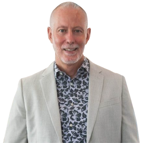 Man in a light blazer and patterned shirt smiling against a white background
