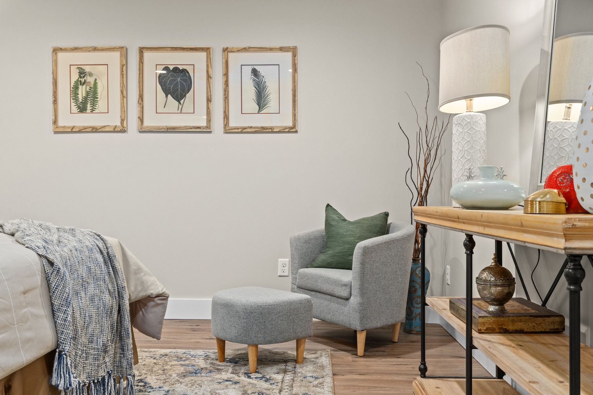 Cozy living room with gray chair, framed wall art, floor lamp, and wooden side table.
