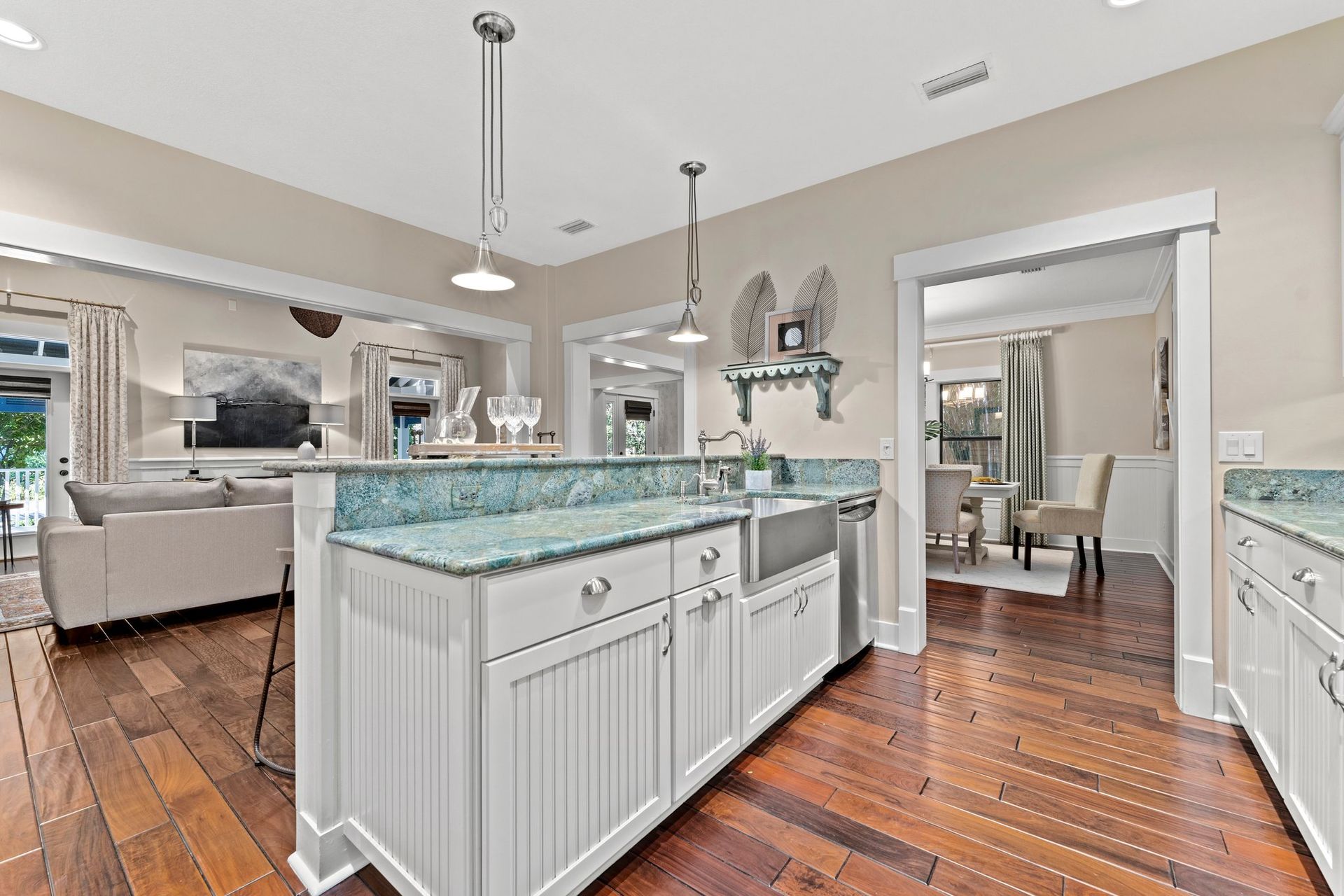 Bright open kitchen with a white island, blue countertops, and hardwood floors, opening to a dining area