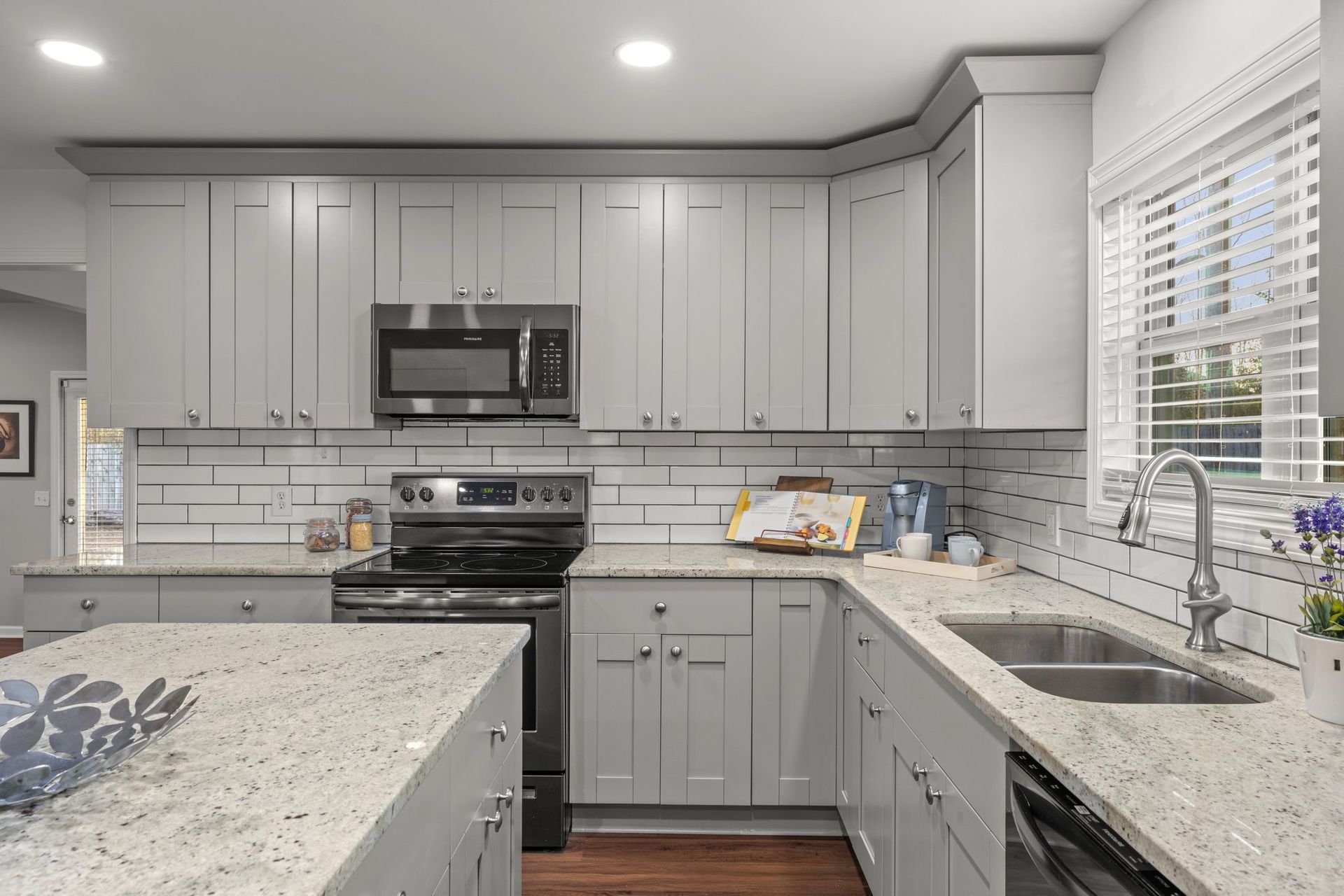 Modern gray kitchen with white countertops, stainless appliances, and a window over the sink
