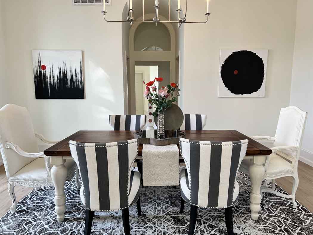Elegant dining room with striped chairs, dark wood table, patterned rug, and floral centerpiece