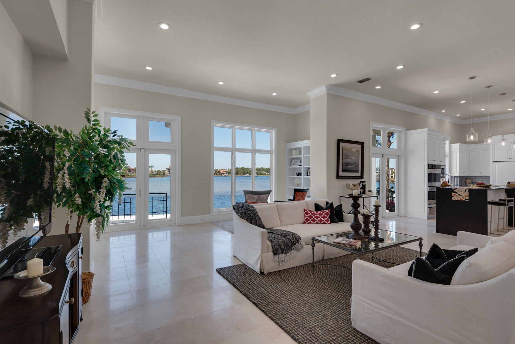 Bright, open living room with white sofas, large windows, and a view of the water.