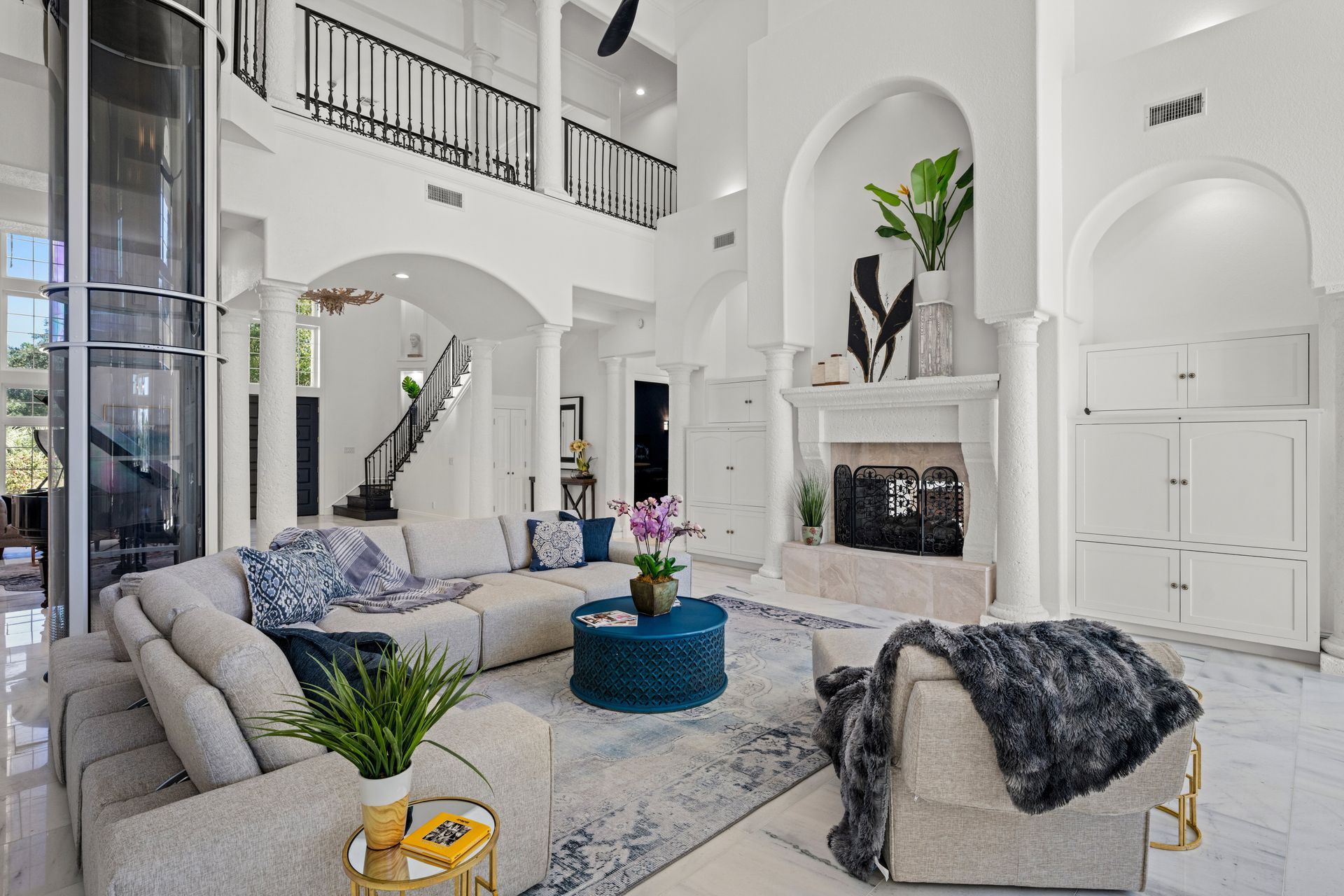 Bright modern living room with white walls, arched openings, blue accents, and a fireplace