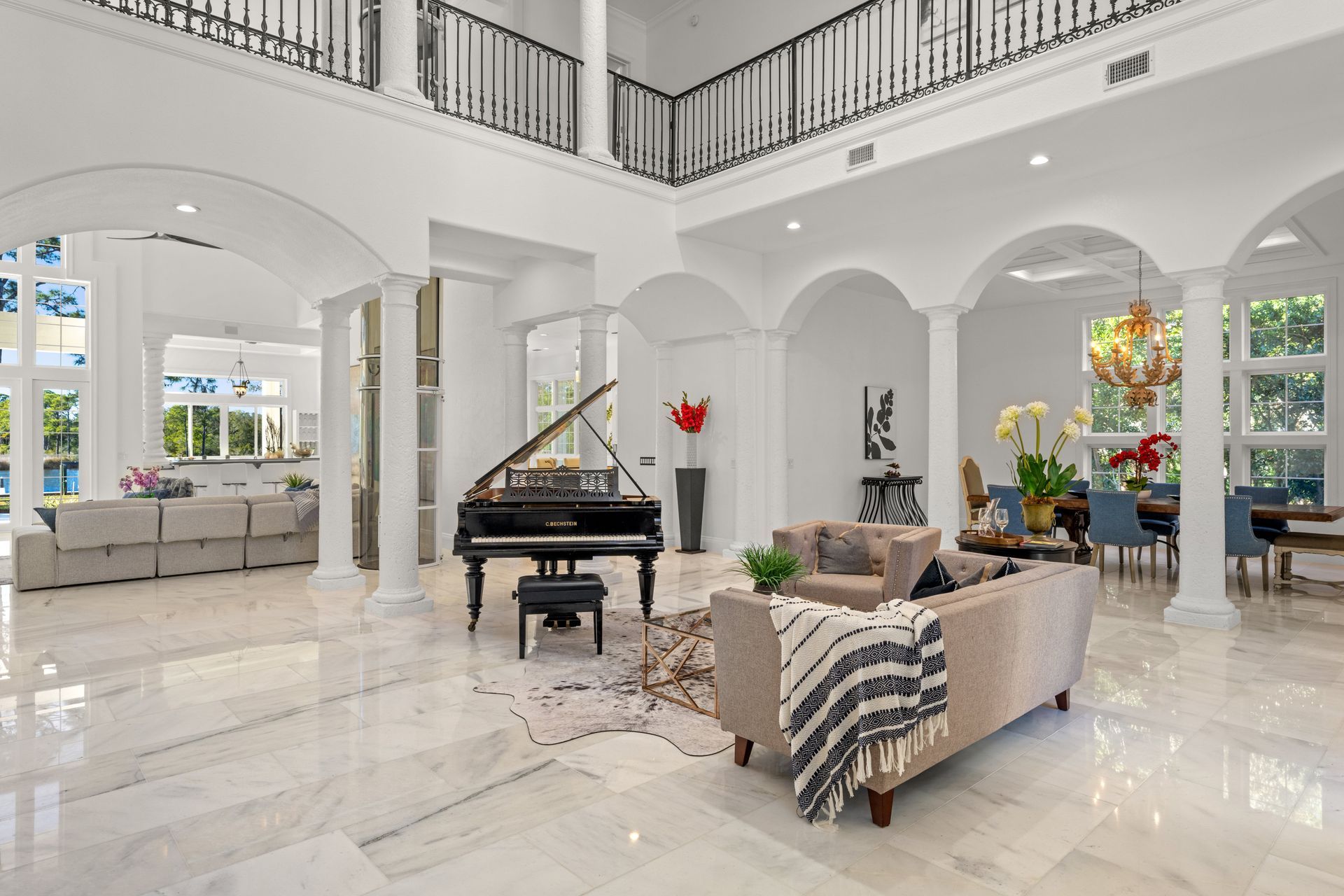 Bright modern living room with white arches, grand piano, beige sofas, and glossy marble floors.