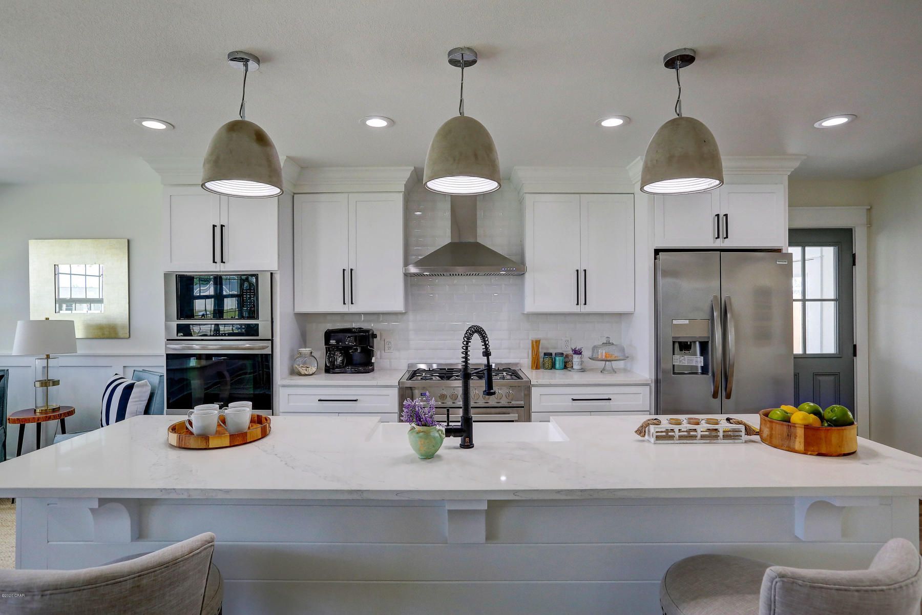 Bright modern kitchen with white cabinets, large island, pendant lights, and stainless steel appliances