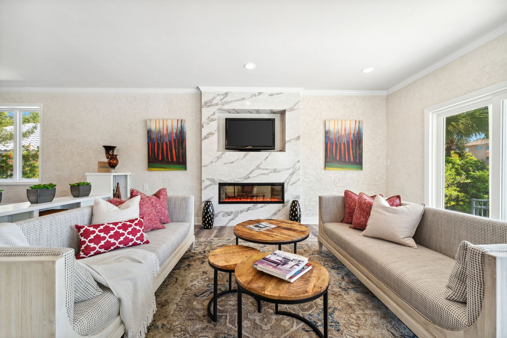 Bright living room with two sofas, patterned pillows, a fireplace, TV, and round coffee tables