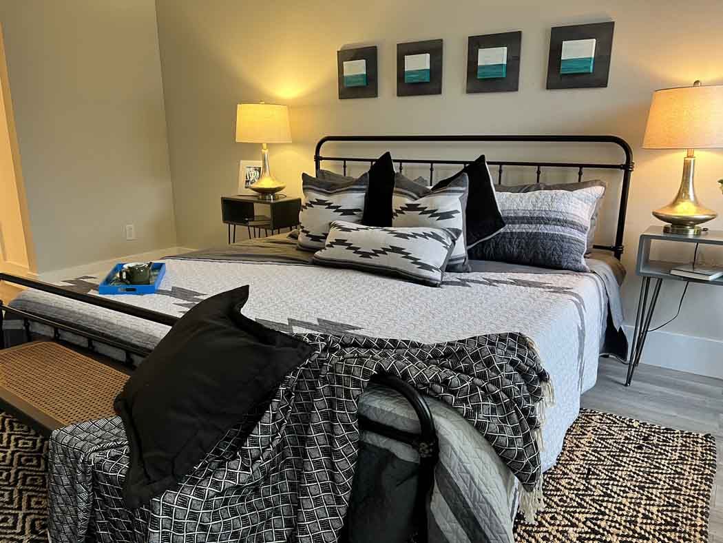 Cozy bedroom with a black metal bed, patterned bedding, lamps, and framed wall art