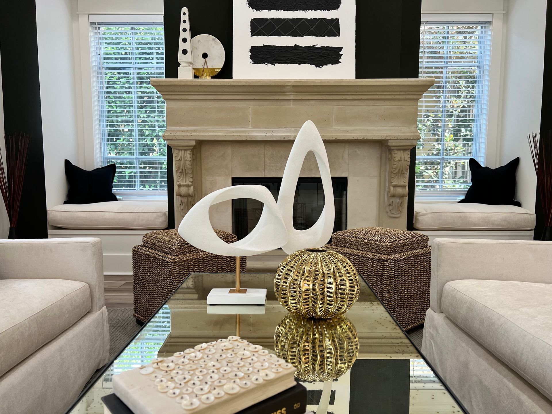 Modern living room with white sofa, glass coffee table, abstract sculpture, and black-and-white decor
