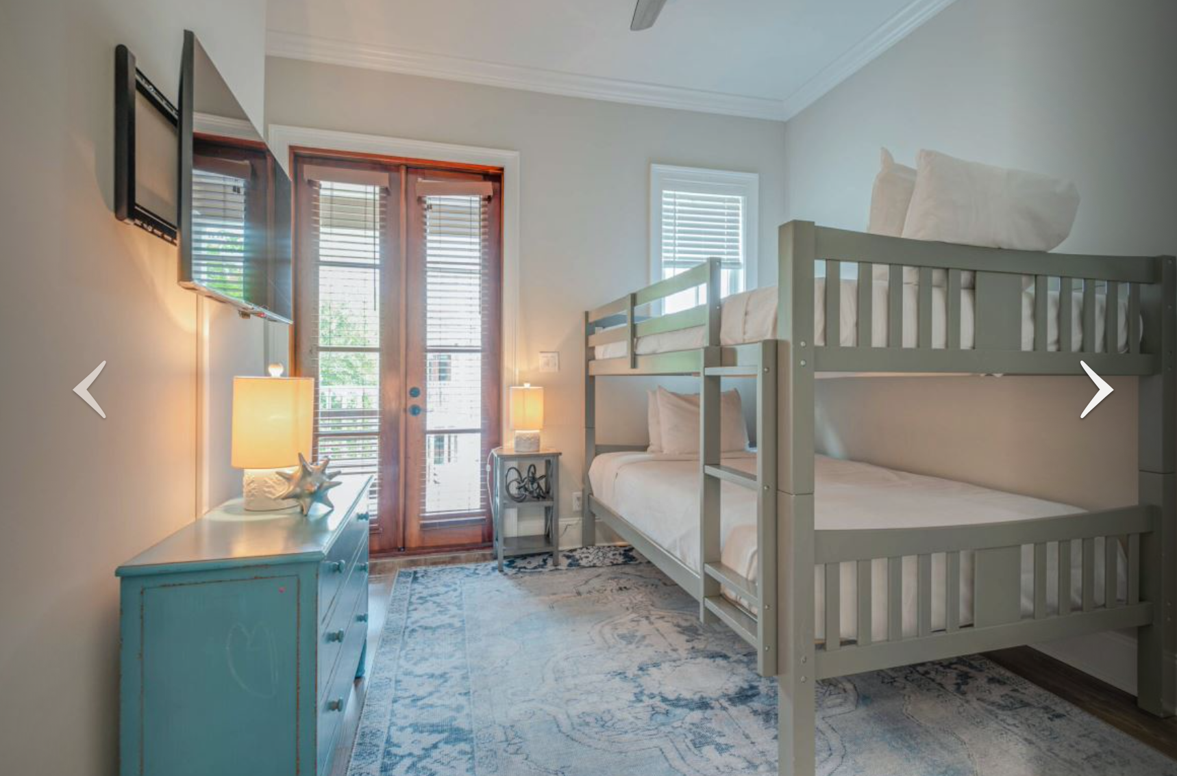 Small bedroom with bunk beds, teal dresser, and French doors opening to a balcony.