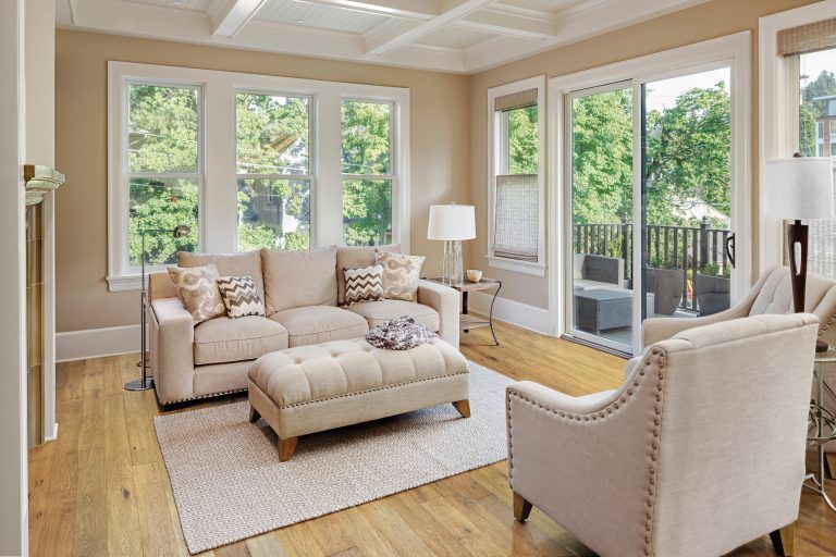 A living room with a couch , chairs , ottoman and sliding glass doors.