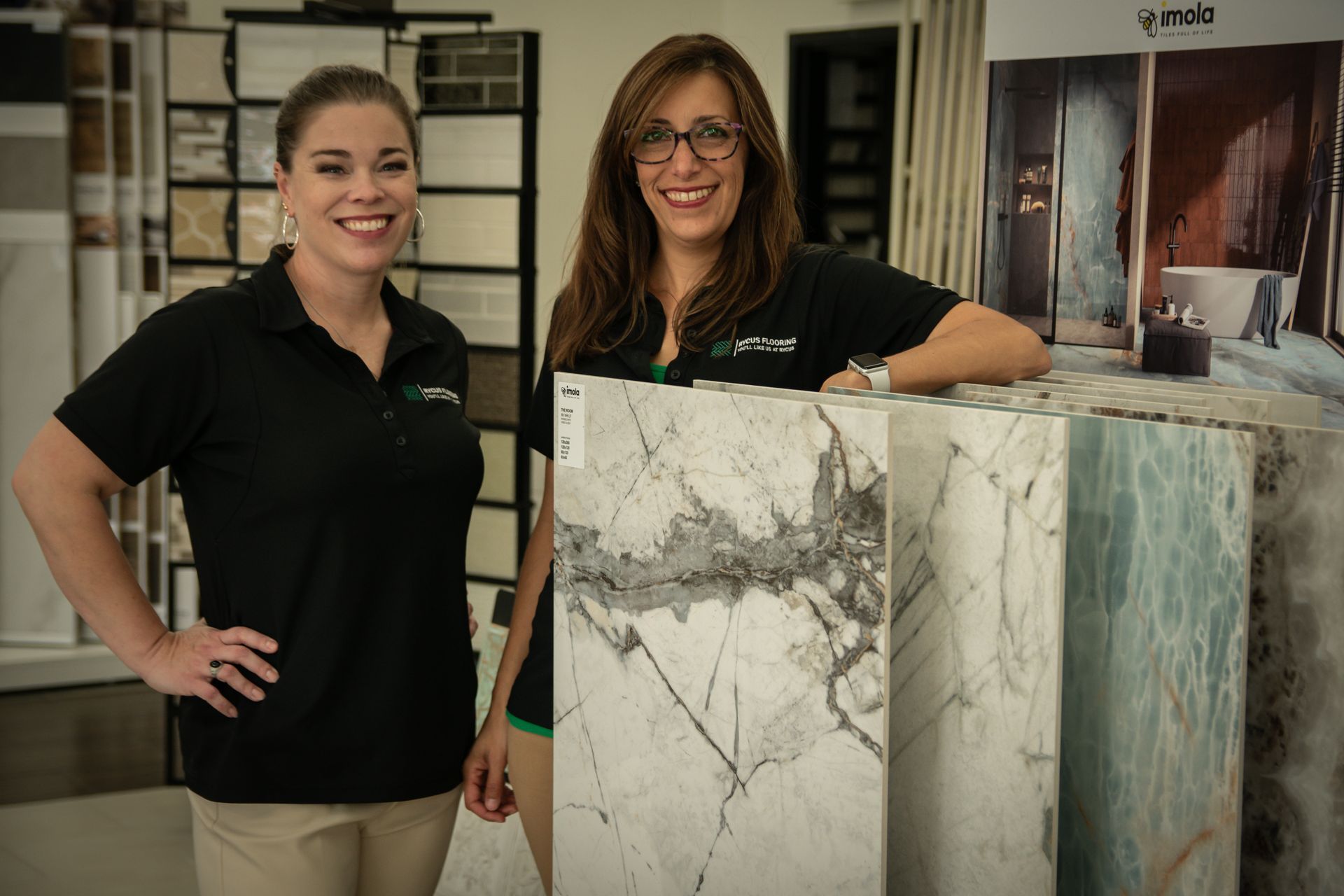 Two women are standing next to each other in a store holding marble slabs.